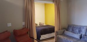 卡内拉Apto Bell Canela "Cobertura no Centro"的一间卧室配有一张床、一把椅子和镜子