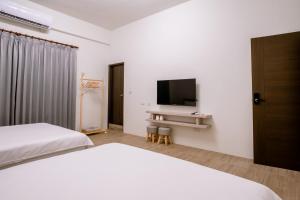 Huxi澎湖逸軒居民宿的一间卧室配有两张床和一台平面电视