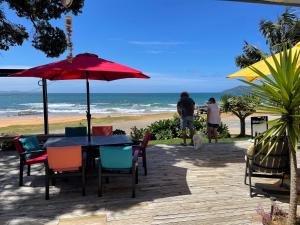 库珀海滩Driftwood Beachfront Accommodation, Cable Bay, Owhetu的海滩上的桌椅和遮阳伞