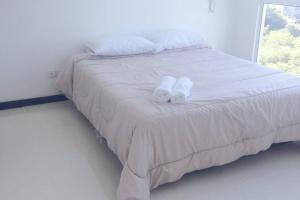 圣玛尔塔Pozos colorado Bello horizonte - Apartamento 70 mt2的一张白色的床,上面有两条毛巾