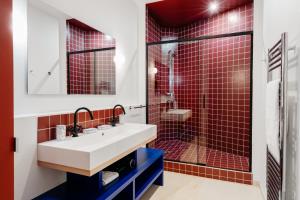 巴黎Edgar Suites Auteuil - Le Marois的浴室设有水槽和红色瓷砖淋浴。