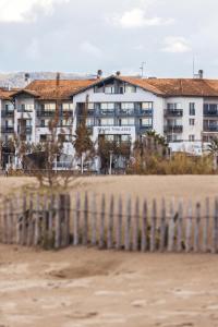 昂代四星塞尔吉布兰科Spa酒店的海滩上的建筑,带有栅栏