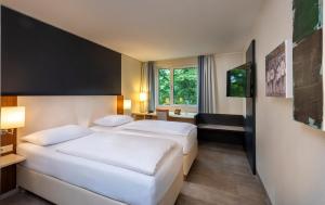 科隆Essential by Dorint Köln-Junkersdorf的酒店客房设有两张床和窗户。