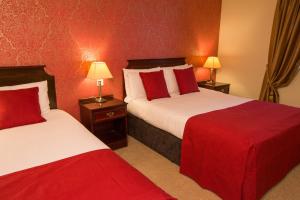 瑟勒斯安奈酒店的红色墙壁的酒店客房内的两张床