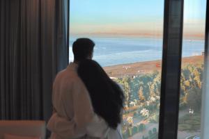 巴统MiraMar Luxury Residences的看着窗外大海的女人