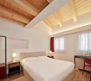 的里雅斯特Crocevia - Locanda carsica contemporanea的卧室设有白色大床和木制天花板。