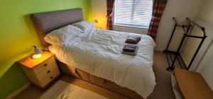 伦敦SW19 - Quiet split-level 2-bedroom maisonette with garden的一间卧室配有一张带白色床单的床和一扇窗户。