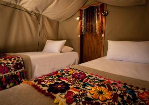 乌鲁班巴Glamping Chaska Ocupi的一间设有两张床的房间,上面有毯子