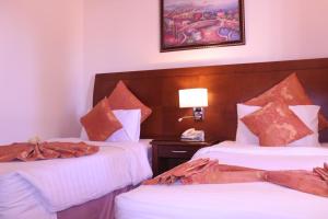 瓦迪穆萨阿姆拉王宫国际酒店的酒店客房设有两张床和一张带台灯的桌子。