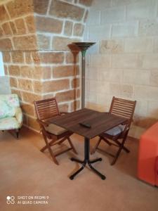 布林迪西La conigliera的一张木桌,配有两把椅子和一盏灯
