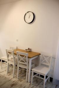 格但斯克P&K Motlawa Apartment的餐桌和椅子,墙上挂着时钟