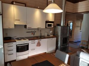 索特Air-conditioned holiday home Vutnusmaja at Iso-Syöte的厨房配有白色橱柜和炉灶烤箱。