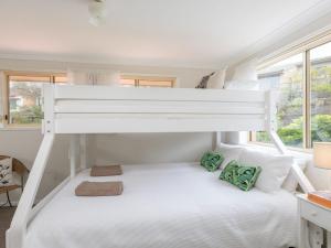 凯阿玛Tehidy Townhouse的一间卧室配有双层床、白色床单和绿色枕头