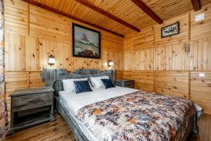 米库利钦Emerald House的卧室配有一张床铺,位于带木墙的房间内