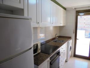 佩尼斯科拉Apartamentos Alboran 4/6 LEK的厨房配有白色橱柜、水槽和冰箱。