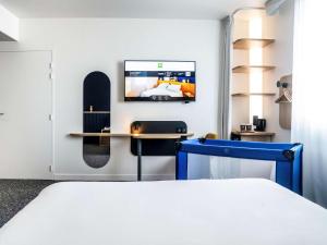 罗曼维尔ibis Styles Paris Romainville的一间卧室配有一张床,墙上配有电视