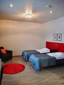 卡拉约基Safarimajoitus的一间设有三张床和一把椅子的房间,铺有红色地毯