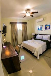 拉罗马纳Halibut Hotel的一间卧室配有一张床、一张桌子和吊扇