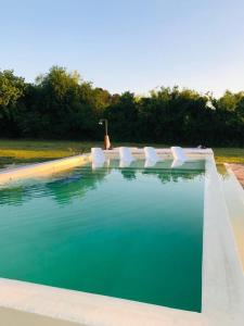 埃斯基纳La Mansa Riverside的一个带白色椅子和蓝色水的游泳池