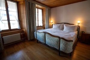 格吕耶尔百合花酒店的一间卧室配有一张带白色床单的床和两个窗户。