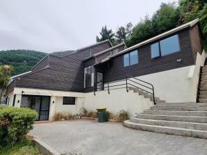 皇后镇Queenstown Lakeview Holiday Home-5mins to town的黑色屋顶和楼梯的房子