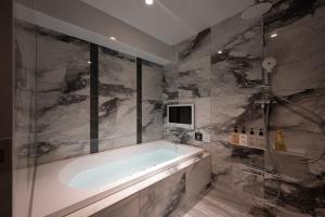 东京HOTEL VARKIN Ikebukuro Nishiguchi的带浴缸的浴室和墙上的电视