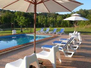 米尔芳提斯城Monte Do Adail Turismo Rural Casa De Campo的一组椅子和遮阳伞,位于游泳池旁