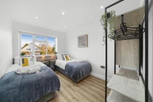 梅德斯通Modern Bungalow in Maidstone sleeps 5 with free parking的一间卧室设有两张床、一张桌子和一个窗口。