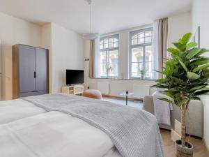 莱比锡limehome Leipzig Oelßner's Hof的卧室配有白色的床和盆栽植物
