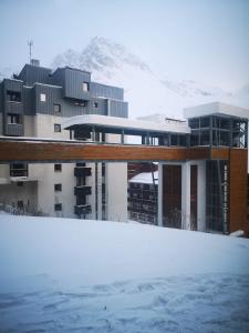 蒂涅Great 8-pax ski-in ski-out apartment in Tignes Val Claret的一座雪地中的建筑,背景是一座山