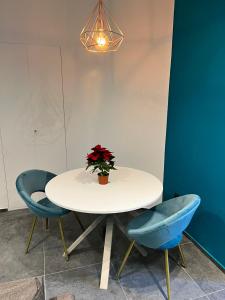 那不勒斯ORLANDO relais的一张带两把蓝色椅子的白色桌子和一个花瓶与植物