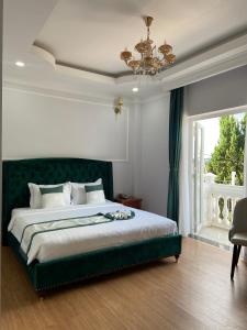 大叻Peach Valley Hotel Dalat的一间卧室配有一张带绿色床头板的床和窗户