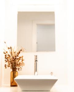 维迪堡A BURGUESA - GUESTHOUSE的浴室水槽设有镜子和花瓶