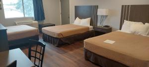 卡尔卡斯卡Rodeway Inn Kalkaska的酒店客房设有两张床和一张桌子。