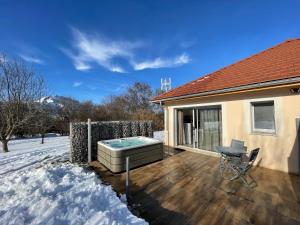 尚普索地区圣博内"Le Cottage" Appartements avec SPA privatif的雪中房子甲板上的热水浴缸