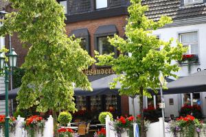 Elten德斯餐厅及酒店的餐厅的前面有两棵树,有桌子和遮阳伞