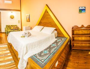 塞尔苏拉穆斯州长镇Pousada Casa do Oscar的一间卧室配有一张大床和木制床头板