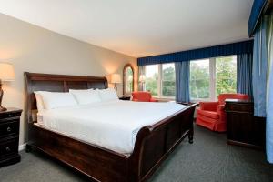 伍德斯托克伍德斯托克夏尔酒店的一间卧室配有一张大床和一张红色椅子
