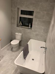 斯内蒂瑟姆Immaculate 2-Bed Bungalow in Snettisham的带浴缸、卫生间和窗户的浴室