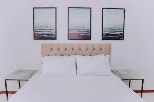 布希奥斯Pousada Peninsula de Buzios的卧室配有一张白色床,墙上挂有4张照片