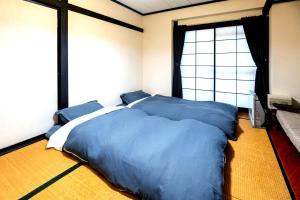 野沢Nozawa Onsen BASECAMP的一间卧室配有一张带蓝色床单的床和一扇窗户。