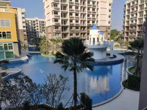 南芭堤雅Super 1BDR in Water Park Resort的享有游泳池、棕榈树和建筑的景色