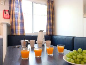 洛萨皮内塔Holiday Home Rosapineta Camping Village-2 by Interhome的一张桌子,上面放着四杯橙汁和一碗葡萄