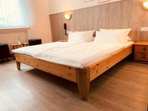 克尔伯Hotel Orthwein -kostenfreie Parkplätze-的卧室内的一张大床,配有木制床头板