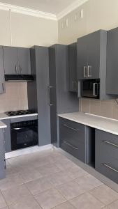 东伦敦Ikhwezi guest house的厨房配有灰色橱柜和炉灶烤箱