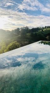 加姆波勒Riverbank Resort Gampola的水面上映着天空的游泳池