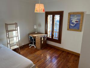 布里昂松Plein soleil的一间卧室配有一张床、一张书桌和一个窗户。