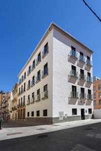 马拉加limehome Málaga Calle Ancha del Carmen - Digital Access的白色的建筑,在街上设有阳台