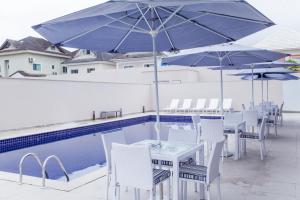 里约热内卢Americas Townhouse Hotel的游泳池畔的桌椅和遮阳伞