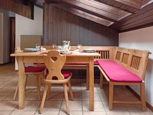 阿尔巴迪卡纳泽伊MANSARDA MARMOLADA sui campi da sci的一张木桌和椅子,配有粉红色的垫子